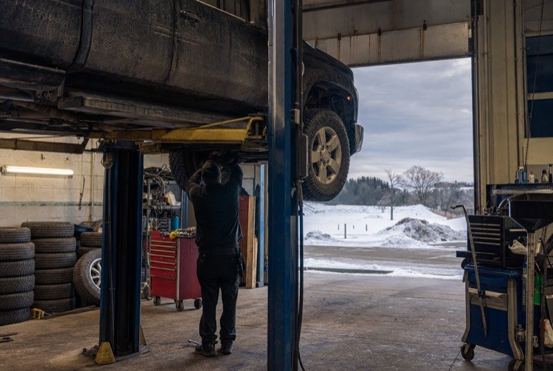 A pickup truck on a hoist with winter tires stacked along the wall, the rush that auto repair SEO plans for