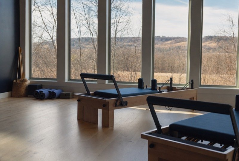 A small studio with yoga mats and reformer machines in morning light