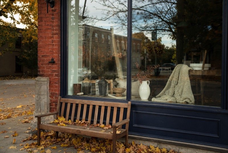 A boutique window display in a red-brick building on a main street in autumn